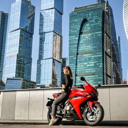 Un hombre toma una fotografía de una mujer posando en una motocicleta frente al Centro Internacional de Negocios de Moscú. | Foto:ALEXANDER NEMENOV / AFP