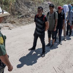 Migrantes de Venezuela hacen fila frente a un agente de la Patrulla Fronteriza de EE. UU. antes de caminar hacia un área de procesamiento después de cruzar el Río Grande en Eagle Pass, Texas. | Foto:ANDREW CABALLERO-REYNOLDS / AFP