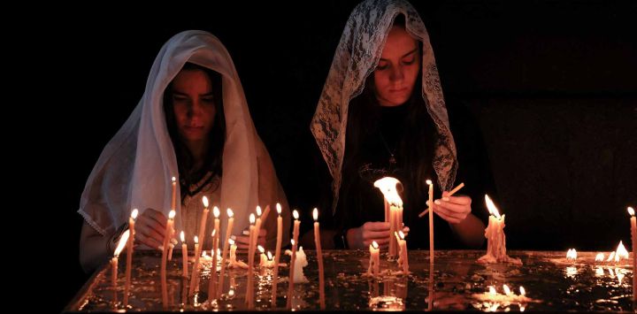 Los fieles encienden velas y rezan durante un servicio por los refugiados de Nagorno Karabaj en la iglesia vicarial de Saint-Sargis como parte de la oración nacional por el día de Artsaj en Ereván. Foto de ALAIN JOCARD / AFP