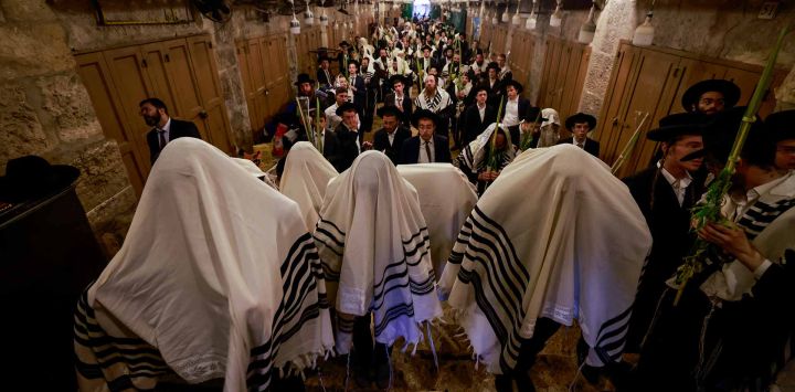 Hombres judíos, vestidos con chales de oración tradicionales conocidos como Tallit, se reúnen en la Puerta de los Comerciantes de Algodón en la ciudad vieja de Jerusalén. Foto de Menahem KAHANA / AFP