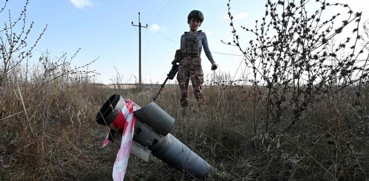Un desminador del fondo benéfico "Desminado de Ucrania" junto a un proyectil sin explotar en un campo cerca de la ciudad de Derhachi, región de Járkov. Foto de SERGEY BOBOK / AFP