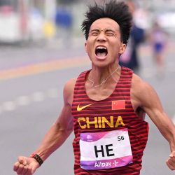 He Jie de China celebra después de cruzar la línea de meta para ganar la final de atletismo de maratón masculino durante los Juegos Asiáticos. Foto de WILLIAM WEST / AFP | Foto:AFP