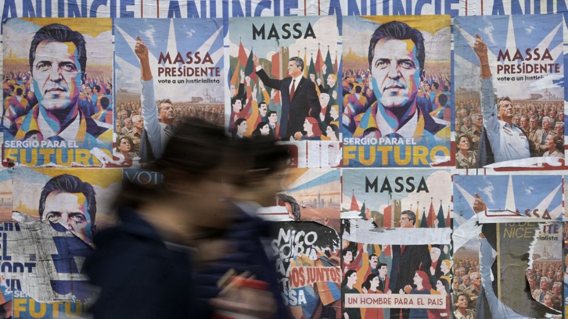 People walk past electoral campaign posters promoting economy minister and presidential candidate for the ruling Unión por la Patria coalition, Sergio Massa in Buenos Aires on October 3, 2023, ahead of Argentina's presidential election to be held on October 22. 