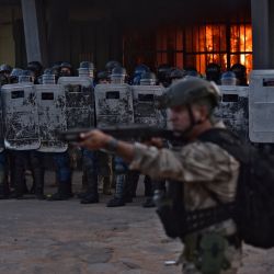 Las fuerzas de seguridad hacen guardia mientras arde un incendio dentro de la prisión de Tacumbu después de que cientos de reclusos tomaran las instalaciones, en Asunción, Paraguay. | Foto:NORBERTO DUARTE/AFP