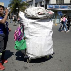 Cartonera Ayelen Torres, a worker of the 'Cooperativa Construyendo Desde Abajo', drinks water next to her cart during her workday collecting recyclables in San Justo, La Matanza, Buenos Aires province, on October 5, 2023.