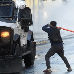 Un manifestante se enfrenta a policías antidisturbios durante una protesta para conmemorar el aniversario del estallido social de 2019 en Santiago, Chile. | Foto:Pablo Vera/AFP