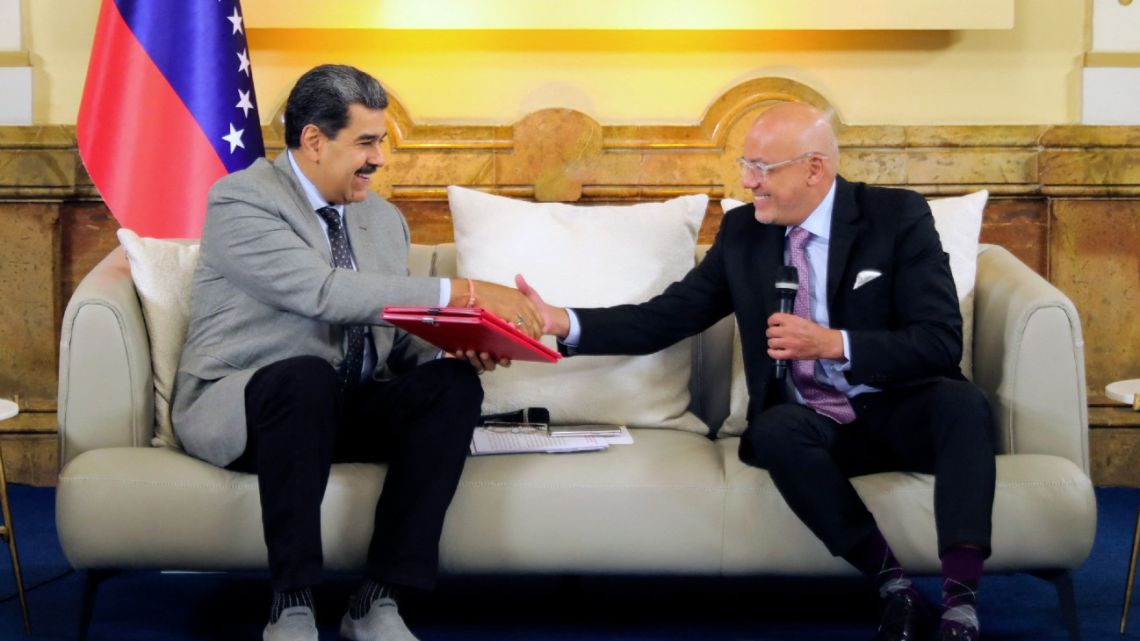 Venezuela's President Nicolas Maduro (L) shaking hands with Venezuela's National Assembly President Jorge Rodriguez during a meeting after signing an agreement between the Venezuelan government and opposition talks in Barbados at the Miraflores presidential palace in Caracas 
