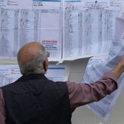 Un elector revisa el censo electoral mojado por la lluvia a la entrada de un colegio electoral en Buenos Aires, durante las elecciones presidenciales. | Foto:JUAN MABROMATA/AFP