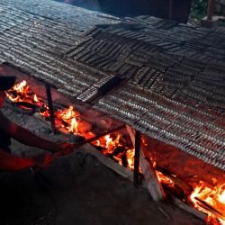 Una familia asa brochetas de pescado en su casa en la provincia de Kandal, Camboya. | Foto:TANG CHHIN SOTHY / AFP