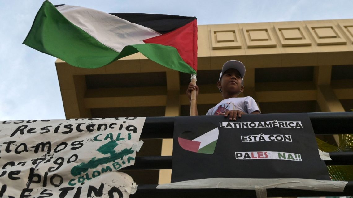 A boy holds a Palestine flag next to a sign that reads “Latin America is with Palestine" during a demonstration in support of Palestinians in Cali, Colombia, on October 19, 2023