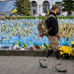 Un militar, con piernas ortopédicas, pasa junto a las banderas ucranianas que simbolizan a los soldados caídos en la Plaza de la Independencia en Kiev, en medio de la invasión rusa de Ucrania. | Foto:SERGEI SUPINSKY / AFP
