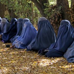 Mujeres afganas vestidas con burkas sentadas mientras esperan recibir dinero en efectivo del Alto Comisionado de las Naciones Unidas para los Refugiados (ACNUR), en Ghazni. | Foto:Mohammad Faisal Naweed / AFP