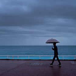 Un hombre con un paraguas camina por el "Promenade des anglais" en la ciudad de Niza, en la Riviera francesa. | Foto:VALERY HACHE / AFP