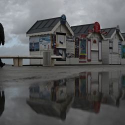 Un hombre camina junto a las taquillas cerradas de excursiones marítimas y se refleja en un charco de agua después de las fuertes lluvias previas a la tormenta Ciaran, en Arcachon, suroeste de Francia. | Foto:PHILIPPE LÓPEZ / AFP