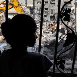 Una niña se encuentra detrás de la malla metálica que cubría la ventana de un edificio que fue alcanzado por un bombardeo israelí en Rafah, en el sur de la Franja de Gaza, en medio de las batallas en curso entre Israel y el movimiento palestino Hamas. | Foto:MOHAMMED ABED / AFP