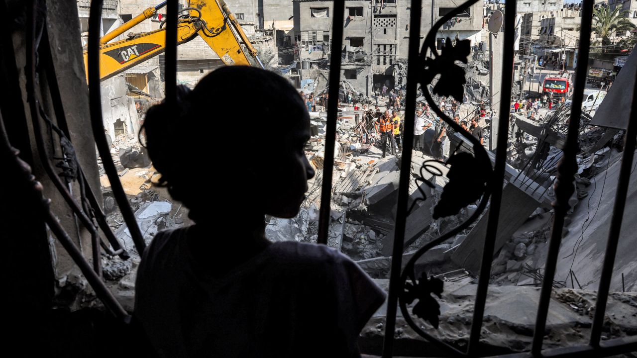 Una niña se encuentra detrás de la malla metálica que cubría la ventana de un edificio que fue alcanzado por un bombardeo israelí en Rafah, en el sur de la Franja de Gaza, en medio de las batallas en curso entre Israel y el movimiento palestino Hamas. | Foto:MOHAMMED ABED / AFP