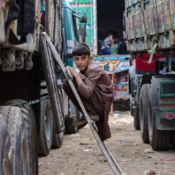 Un niño refugiado afgano sube a un camión mientras se prepara para partir hacia Afganistán, en un centro de detención en Landi Kotal. | Foto:Farooq Naeem / AFP