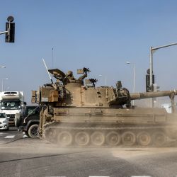 Un obús de artillería autopropulsado del ejército israelí pasa entre el tráfico que espera mientras cruza una carretera a lo largo de la frontera con la Franja de Gaza en el sur de Israel en medio de batallas en curso entre las fuerzas israelíes y el movimiento palestino Hamas. | Foto:MENAHEM KAHANA / AFP
