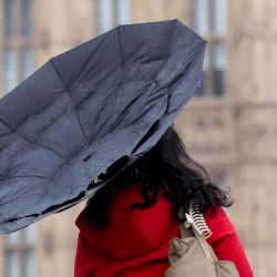 Imagen de una mujer luchando por sostener un paraguas en el puente de Westminster, en el centro de Londres, Reino Unido. | Foto:Xinhua