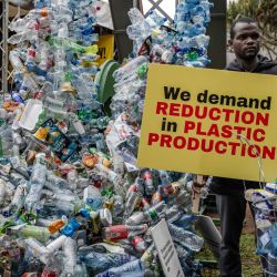 Un activista climático sostiene una pancarta junto a una instalación de plástico después de marchar para exigir una reducción drástica en la producción mundial de plástico durante la Marcha del Movimiento Liberarse del Plástico antes de la tercera reunión del Comité Intergubernamental de Negociación en Nairobi. | Foto:LUIS TATO/AFP