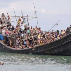 Tres refugiados rohingya recién llegados intentan nadar hasta la playa mientras están varados en un barco después de que la comunidad cercana les dio agua y comida pero no les permitió desembarcar en Pineung, provincia de Aceh, Indonesia. | Foto:Amanda Jufrian /AFP