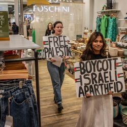 Activistas sudafricanos del Boicot, Desinversión y Sanciones (BDS) sostienen pancartas con lemas en apoyo de los territorios palestinos dentro de una tienda mientras participan en un piquete en el Rosebank Mall en Johannesburgo contra la cadena minorista sudafricana Cape Union Mart durante una Acción a nivel nacional. | Foto:STRINGER / AFP