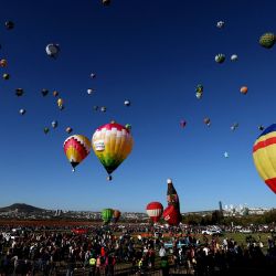 Un grupo de personas observa cómo se elevan los globos aerostáticos durante el 21º Festival Internacional de Globos Aerostáticos en León, estado de Guanajuato, México. | Foto:ULISES RUIZ / AFP