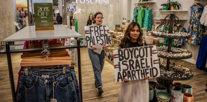 Activistas sudafricanos del Boicot, Desinversión y Sanciones (BDS) sostienen pancartas con lemas en apoyo de los territorios palestinos dentro de una tienda mientras participan en un piquete en el Rosebank Mall en Johannesburgo contra la cadena minorista sudafricana Cape Union Mart durante una Acción a nivel nacional.