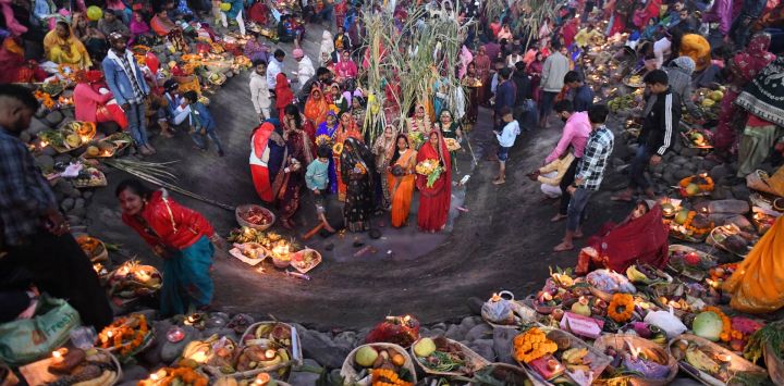 Los devotos realizan rituales religiosos mientras ofrecen oraciones al dios Sol mientras están de pie en las aguas de un lago con motivo del festival hindú de Chhat Puja en Chandigarh.