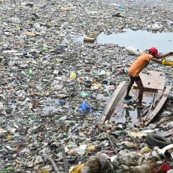 Un trabajador municipal limpia residuos de plástico y basura que obstruyen el flujo de agua del canal de Buckingham en Chennai, India. | Foto:R. Satish Babu / AFP