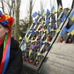 Una joven que lleva una corona ucraniana, posa en el monumento a los activistas de Maidan, también conocidos como "Héroes de los Cien Celestiales", en referencia a las personas asesinadas en las manifestaciones antigubernamentales de 2013-2014, en Kiev. | Foto:SERGEI SUPINSKY / AFP