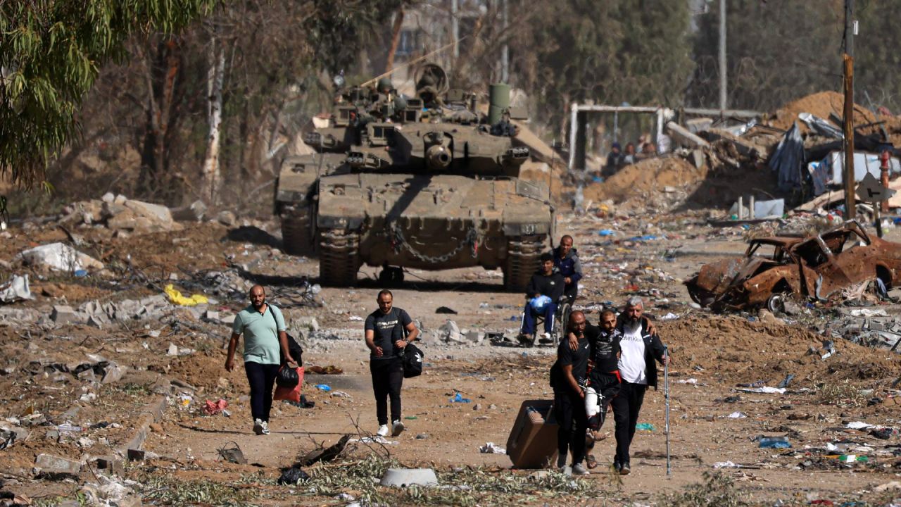 Palestinos que huyen hacia el norte a través de la carretera Salaheddine en el distrito de Zeitoun en las afueras del sur de la ciudad de Gaza, pasan junto a tanques del ejército israelí, luego de un alto el fuego de cuatro días que comenzó temprano en la mañana. La tregua en la guerra entre Israel y Hamas entró en vigor a las 07.00 hs. y parecía mantenerse, bajo un acuerdo que permitirá la liberación de rehenes a cambio de prisioneros palestinos. | Foto:MAHMUD HAMS / AFP