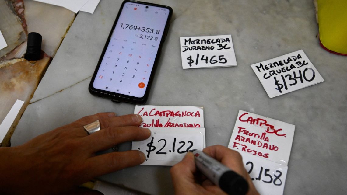 Paola Basso, owner of a supermarket, writes on labels the new prices of the products at her supermarket in Morón, Buenos Aires Province.