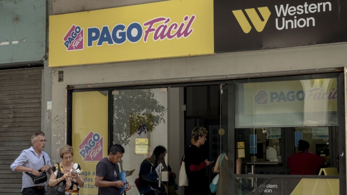 Customers wait in line at a branch of Western Union and PagoFacil in Buenos Aires City.