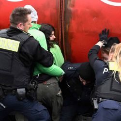 Agentes de policía intentan retener a activistas del grupo ecologista Greenpeace mientras organizan una protesta con un barril de petróleo frente a la Cancillería en Berlín. Foto de Tobias SCHWARZ / AFP | Foto:AFP