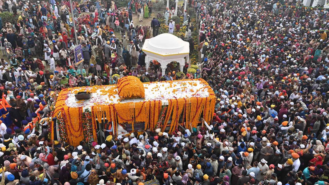 Los devotos sikh se reúnen alrededor de un autobús que transporta el Guru Granth Sahib (libro sagrado sikh) durante una procesión religiosa con motivo del aniversario del nacimiento de Guru Nanak Dev. Foto de Arif ALI/AFP | Foto:AFP