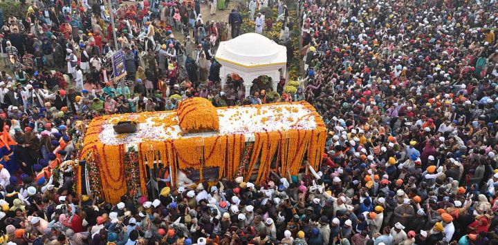 Los devotos sikh se reúnen alrededor de un autobús que transporta el Guru Granth Sahib (libro sagrado sikh) durante una procesión religiosa con motivo del aniversario del nacimiento de Guru Nanak Dev. Foto de Arif ALI/AFP