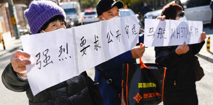 Los familiares de los pasajeros del vuelo MH370 desaparecido de Malaysia Airlines sostienen un cartel que dice "Exigimos firmemente un juicio público de los casos del MH370 de Malaysia Airlines". Foto de Pedro PARDO/AFP