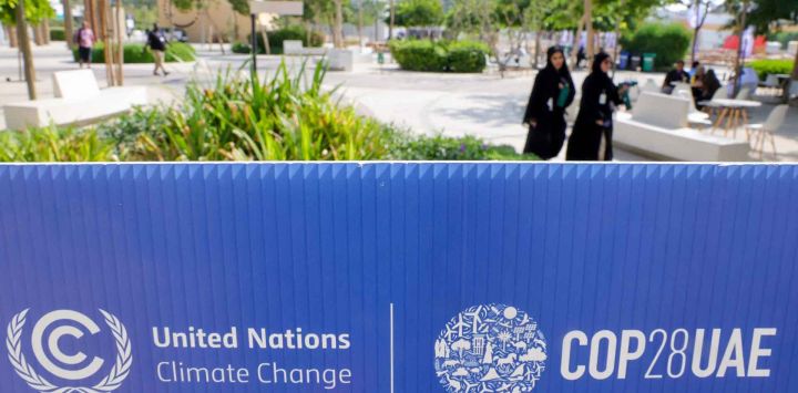 Dos mujeres caminan cerca de un logotipo de la COP28 antes de la cumbre climática de las Naciones Unidas en Dubai. Foto de Giuseppe CACACE / AFP