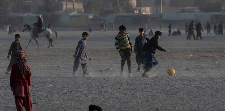 Niños afganos juegan al fútbol en el campo Chaman-e-Huzuri en Kabul. Foto de Wakil KOHSAR / AFP