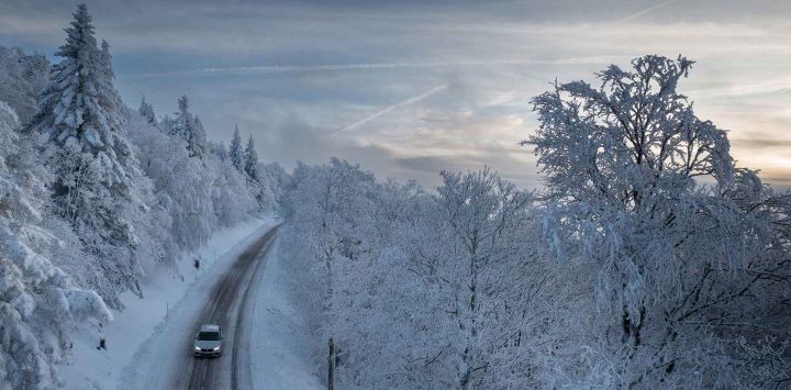 Un automóvil conduciendo por una carretera rodeada por un bosque cubierto de nieve en las montañas de los Vosgos, cerca de Saint-Maurice-sur-Moselle. Foto de SEBASTIEN BOZÓN / AFP 