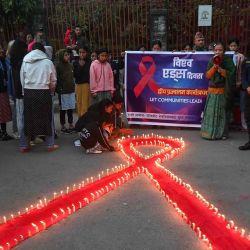 Los voluntarios encienden velas dispuestas en forma de cinta roja durante un evento de sensibilización organizado en vísperas del “Día Mundial del SIDA” en Katmandú. Foto de PRAKASH MATHEMA / AFP | Foto:AFP