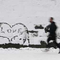 Un hombre corre en la nieve junto a un graffiti en forma de corazón que dice "amor" en Berlín, Alemania. Foto de Tobias SCHWARZ / AFP | Foto:AFP
