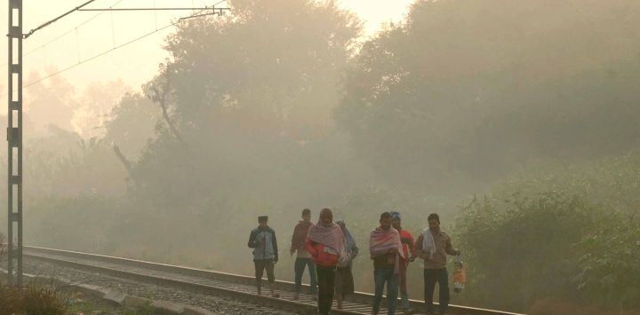 Los trabajadores caminan por una vía de ferrocarril en medio de una densa niebla tóxica en Amritsar. Foto de Narinder NANU / AFP