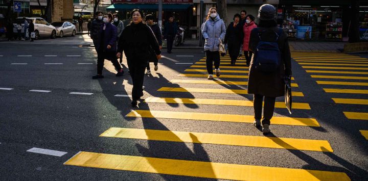 Peatones cruzan una calle en el distrito Jongno de Seúl. Foto de Anthony WALLACE / AFP