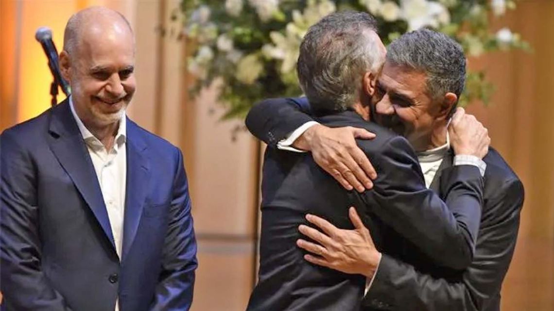 New Buenos Aires City Mayor Jorge Macri is embraced by his cousin, former president Mauricio Macri, as outgoing City mayor Horacio Rodríguez Larreta looks on.