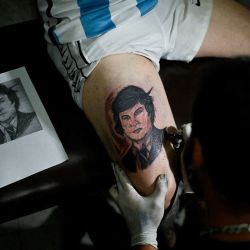 El empleado de la estación de servicio Pablo Vega, de 48 años, votante del presidente electo Javier Milei, se tatua la pierna con una imagen del rostro de Milei en La Matanza, provincia de Buenos Aires. | Foto:LUIS ROBAYO / AFP