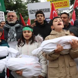 Niños cargan bolsas para cadáveres simuladas durante una manifestación en apoyo de los palestinos cerca de la embajada de Estados Unidos en Ankara, Turquía. | Foto:ADEM ALTAN / AFP