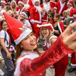 Una mujer disfrazada de Papá Noel se toma una selfie durante la SantaCon anual en Hong Kong. | Foto:PETER PARKS / AFP