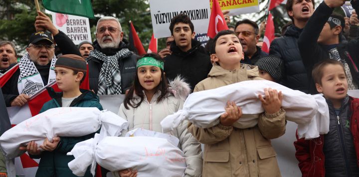 Niños cargan bolsas para cadáveres simuladas durante una manifestación en apoyo de los palestinos cerca de la embajada de Estados Unidos en Ankara, Turquía.